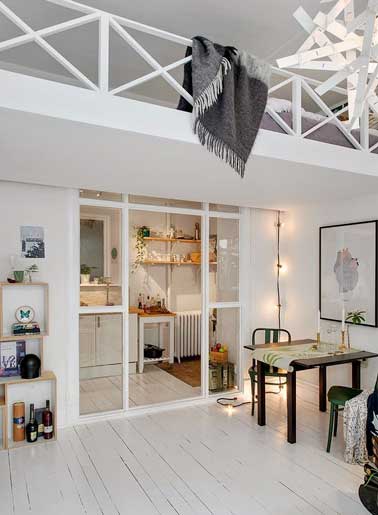 Dans ce petit appartement une verrière intérieur est installée sous la mezzanine pour délimiter ia cuisine du salon. Sa structure peinte en blanc est complètement intégrée à la pièce 