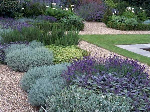 Un jardin zen réalisé avec plusieurs parterre de plantes méditerranéennes entouré de gravillons colorés. Composition symétrique pour entourer un bassin d'extérieur.