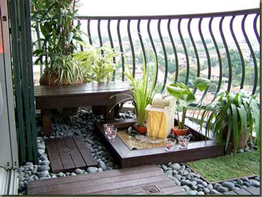 Parterre galet et dalles de jardin en iroko composent ce jardin zen. Une petite fontaine est aménagé dans un carré et décoré avec deux plantes et du sable. 