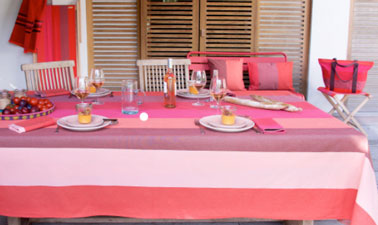 Déclinaison de rayures rouges pour la nappe 250 x 180 cm et les serviettes de table. Coussins sac cabas et pliant Luz Garance assortis au drap de bain nid d’abeille coloris Piment. 