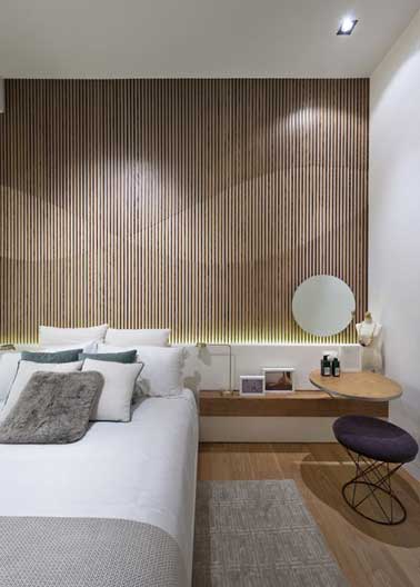 Tête de lit déco graphique dans la chambre avec un panneau décoratif. Table de chevet et tabouret design assortis à la console tête de lit reprennent en écho les formes géométriques du panneau