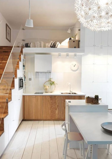 Exemple d’aménagement de cuisine de tiny house avec du parquet blanc. Le sol s’harmonise avec les éléments de cuisine et la table blanche en apportant de la lumière à la petite pièce.