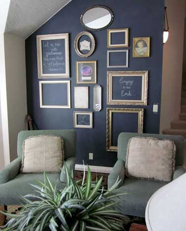 Des cadres vides suspendus contre un mur peint avec une peinture tableau noir font la déco du salon. De toutes les tailles et les formes ils créent une déco cabinet de curiosité