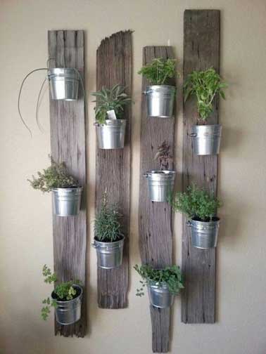 Mur végétal fait avec des pots en fer fixés sur des planches recup. Nettoyées et poncées les planches sont laissées à l’état brut pour faire ressortir les plantes aromatiques 