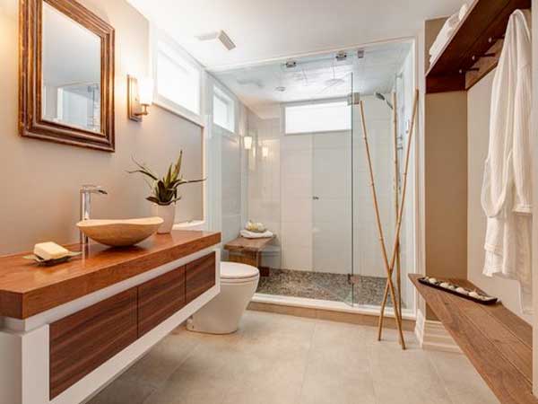 Une salle de bain ambiance zen et naturelle associe banc et plan vasque en bois à un parterre de douche à l'italienne en galets et des joncs de bambous 