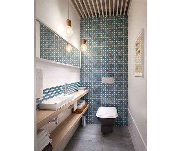 Carreaux de ciment bleu sur les murs de la salle de bain tendance scandinave. Plan vasque, niche et suspensions en bois clair s'harmonisent pour colorer la pièce.
