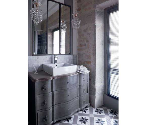 Look rétro dans la salle de bain avec carrelage sol en carreaux de ciment gris. Sublimé par la commode customisée pour recevoir la vasque de lavabo il donne du relief aux murs béton brut.