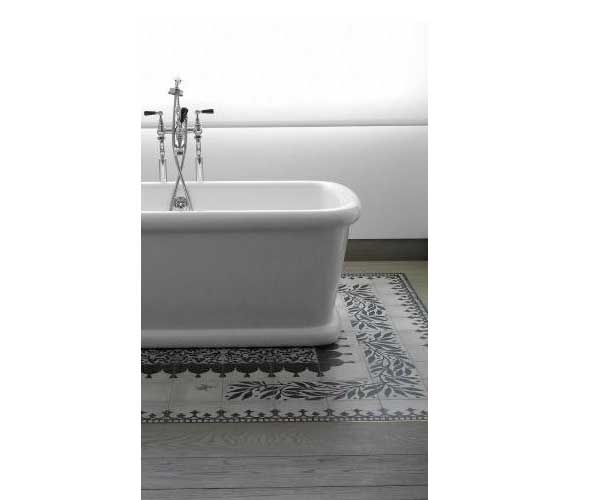 Un tapis de carreaux de ciment est posé sous la baignoire ilot. Simplement marié avec du parquet de salle de bain gris et des murs blancs.