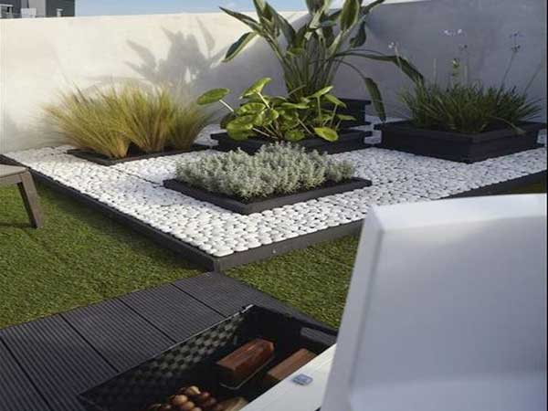 Un coin zen sur la terrasse délimitée avec des galets blancs et plusieurs carrés de plantes vivaces et de plantes grasses