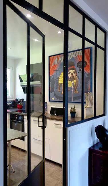 une verrière intérieure avec porte battante sépare l’espace cuisine de l’entrée. En verre et en acier noir, elle ajoute une note industrielle à la déco.