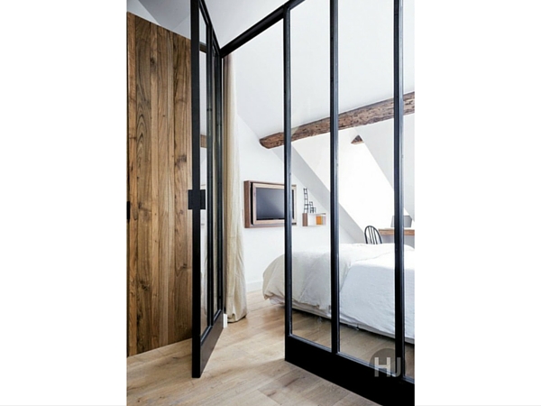 Une verrière industrielle compartimente l’intérieur et définit l’espace sans alourdir dans cette chambre en sous-pente. On aime le contraste entre les montants métalliques et les poutres naturelles. 