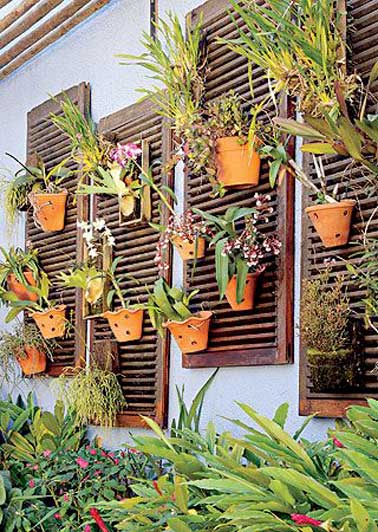 Volets de recup transformés en mur végétal pour faire la déco du jardin et animer le parterre fleuri. Nettoyés et vernis, ils accueillent des plantes en pots sur les persiennes.