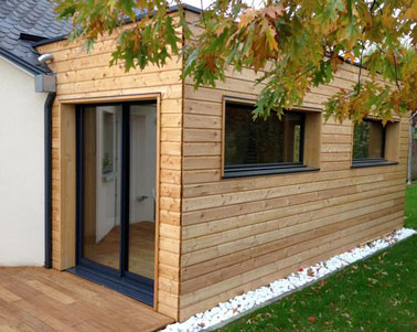 Une extension maison en bois c'est une bonne solution d'agrandissement pour ajouter du cachet à une maison de campagne. Pour assurer une unité, elle est prolongée d'une terrasse en bois.