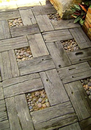 Une allée de jardin avec des planches de bois et des petits galets Ecolo dans l'âme, vous avez envie d'une allée de jardin réalisée avec des matériaux de récup ? Disposez de simples planches en bois dans un motif régulier pour un résultat vraiment sympa !