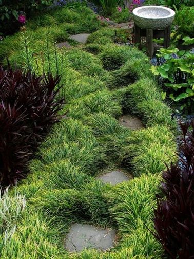 Une allée de jardin japonais bordée de touffes de verdure Un jardin japonais sans allée en pierre, ce n’est pas possible ! Embellissez l’espace entre les pas japonais avec des touffes d’herbes ou de plantes à longues feuilles.