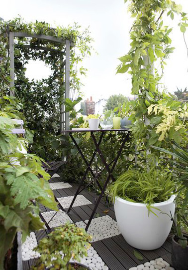 On ne lésine pas sur les plantes vertes pour l’aménagement de ce petit balcon ! Le tout souligné par un beau sol qui alterne dalles de caillebotis en bois et dalles de galets, c'est top