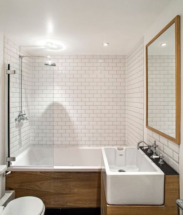 Dans une salle de bain rétro rencontre élégante de carrelage métro sur tous les murs et du bois en habillage de baignoire et de plan vasque. 