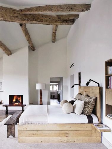 Une chambre avec poutres brutes et un grand lit palette