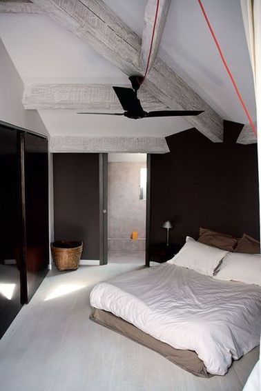 Une chambre avec poutres design aux murs peints en noir