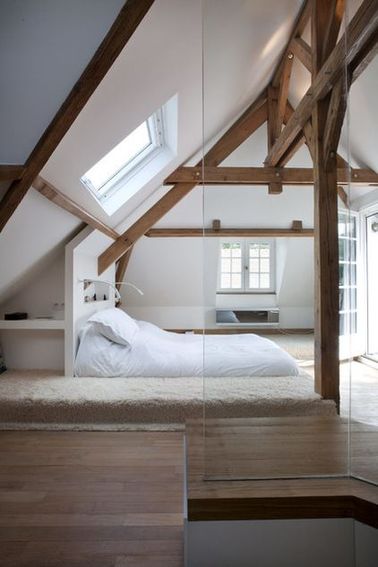 Une chambre avec poutres et un lit sur une estrade