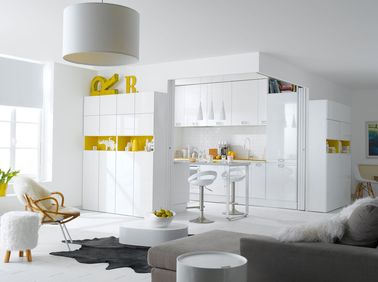 Une cuisine blanche et jaune qui s’ouvre et se ferme suivant vos besoins On a choisi des meubles de salon laqués pour rappeler les éléments de la cuisine blanche. Une bonne intégration pour mettre la préparation des repas au cœur de la maison.