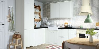 Une cuisine blanche Ikea élégante dans l’esprit campagne chic Une cuisine blanche se prête à tous les styles, comme ici avec un look campagne chic chaleureux rendu par des poignées style ancien, des façades rainurées et une crédence en petits carreaux.