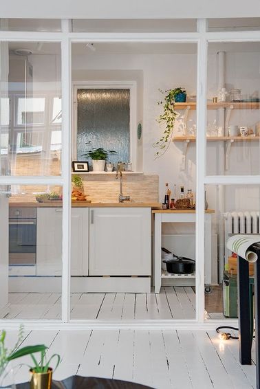 Au lieu de conserver la cloison d’origine, on a ouvert cette cuisine blanche avec une verrière intérieure qui agrandit visuellement l'espace dans ce petit appartement.