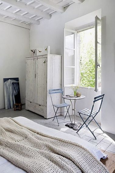 Une déco naturelle dans cette chambre de maison d'été, grâce à une peinture blanche sur les murs et l'armoire ancienne, et un plaid tricoté dans une grosse laine beige.