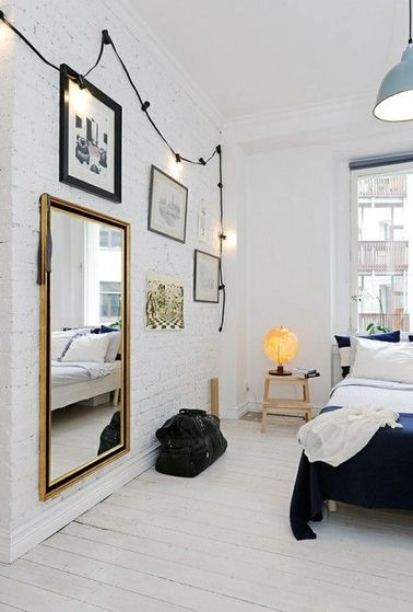 La déco blanche de cette chambre a du caractère grâce à un mur en briques anciennes et un plancher en bois massifs peints en blanc pour mettre un coup de propre.