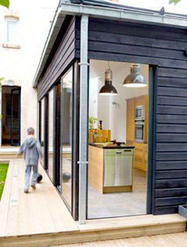 Un agrandissement de maison moderne construit avec une extension entièrement dédiée à la cuisine. L’ossature bois se marie parfaitement avec le style de cet ancien pavillon