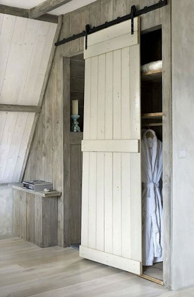 Exemple de cloison coulissante fabriquée avec un volet pour fermer un dressing sous comble. Repeinte avec une peinture blanche, la porte éclaire toute la chambre