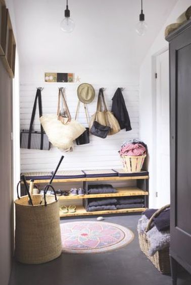 Ce hall d’entrée campagne chic évoque les vacances. Patères fixées sur lambris bois, coussins sur le meuble à chaussures et tapis rond style mandala