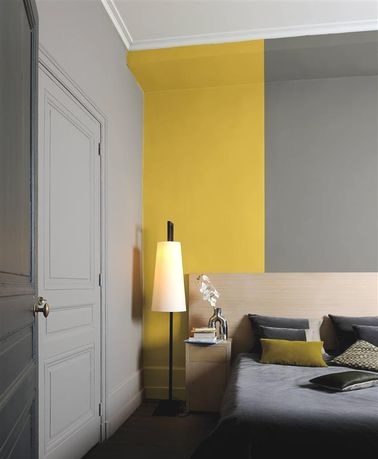 Une peinture chambre avec des accents de jaune pour un aspect contemporain La peinture de cette chambre très originale joue sur les nuances de gris souris et de gris moyen pour faire ressortir un coin recouvert de jaune moutarde qui fait un effet bœuf.