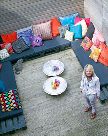 Un salon de jardin aménagé en u avec un grand canapé en palette sur cette terrasse en bois ! Un endroit confortable qui invite à la convivialité pour les soirées d'été 