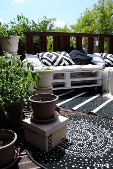 Sur la terrasse, un canapé en palette peint en blanc fait la déco extérieur ! Un petit espace confortable à réaliser pour pas cher et en deux temps trois mouvement 