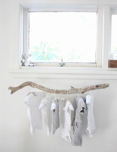 Ce portant à vêtements réalisé en suspendant simplement une branche de bois flotté souligne la déco et l'esprit nature de cette adorable chambre blanche de bébé 