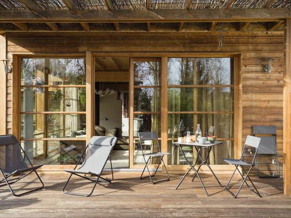 Tables, chaises et fauteuils de jardin se retrouvent sur cette jolie terrasse bois pour une jolie déco et un maxi confort 