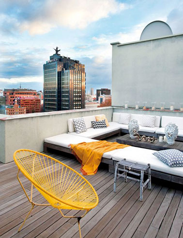 Une terrasse en bois aménagée sur le toit hyper confortable avec un grand salon de jardin et une chaise Acapulco jaune qui fait la déco et met une touche de couleur !