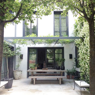 Une jolie terrasse abritée sous un patio où la verdure s'est fait sa place. Un espace extérieur protégé par les plantes et idéalement aménagé pour les repas dans le jardin sans vis à vis