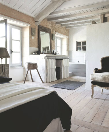 Les poutres apparentes donnent du charme à cette chambre parentale au parquet blanchi et décorée par des couleurs naturelles pour une ambiance douce et apaisante