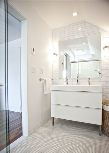 La petite salle de bain s'habille totalement de blanc avec son meuble double vasque ultra pratique et un miroir qui permet d'agrandir la pièce, futé comme idée !
