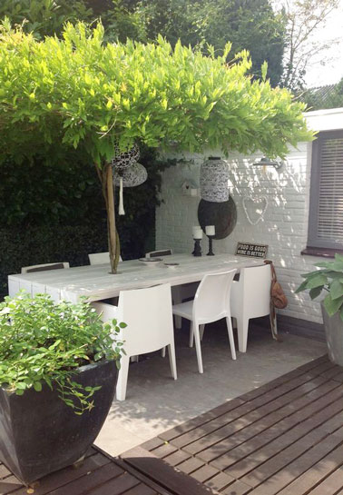 Voilà une déco extérieure qui ne manque pas d'originalité sur la terrasse ! Pour se protéger du soleil et obtenir un espace intime, un grand arbre prend place sur la table et remplace le parasol