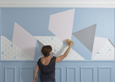 Pour la pose du papier peint au mur, commencez par un angle, chassez les bulles d'air avec une spatule et otez l'excédent de colle avec une éponge humide. 