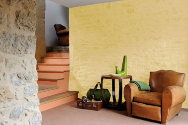 Le mur en pierre peint en jaune sublime les escaliers recouverts de peinture couleur corail. Deux couleurs se mariant joliment pour une déco salon originale et pleine de fraicheur