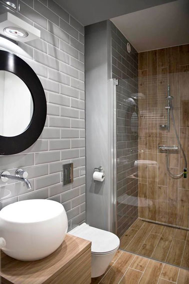 Voilà un mariage subtil entre le bois et le carrelage gris clair pour cette charmante petite salle de bain accueillant une douche italienne moderne et sylée. 