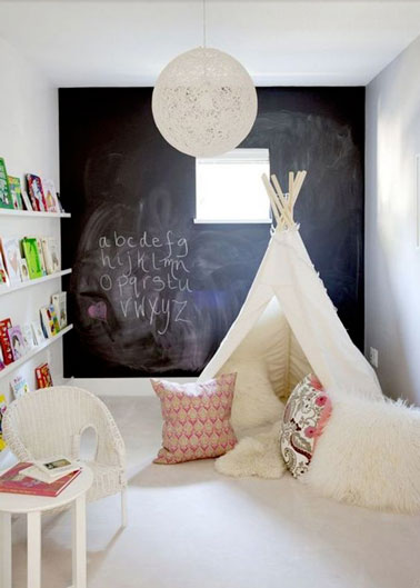 Le tipi fait la déco dans cette salle de jeux pour enfants ! Au fond, un mur peint à la peinture tableau noir pour s'exprimer, un petit coin lecture et voilà une salle de jeux top 