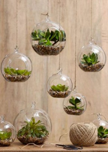 Des terrariums composés de gravier et de plantes suspendus à l’aide d’un fil pour une touche nature dans une déco intérieure. Attention à la lumière pour les plantes.