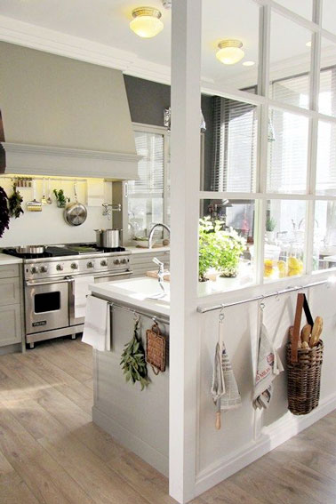 Semi-ouverte sur le salon grâce une verrière intérieure peinte en blanc, cette petite cuisine verrière au parquet blanchi ne manque pas de charme et de luminosité 