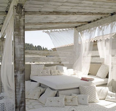 Quel bonheur de pouvoir faire la sieste au sein d'un cadre si agréable ! Sur la terrasse, un lit aménagé avec des coussins et des voilages pour un espace ultra cosy 