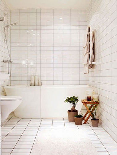 Total look blanc dans cette salle de bain recouverte de carrelage du sol au plafond ! On craque pour la baignoire îlot et les toilettes surélevés pour une ambiance épurée